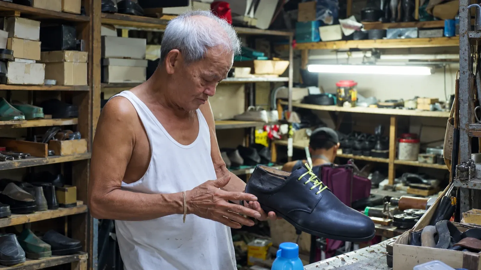 Tatay Oly inspects a shoe as it is being hand-crafted in his workshop