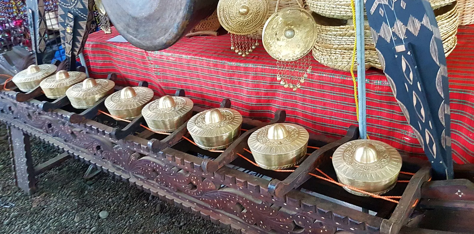 A row of eight bossed kulintang gongs on an ornately carved stand.