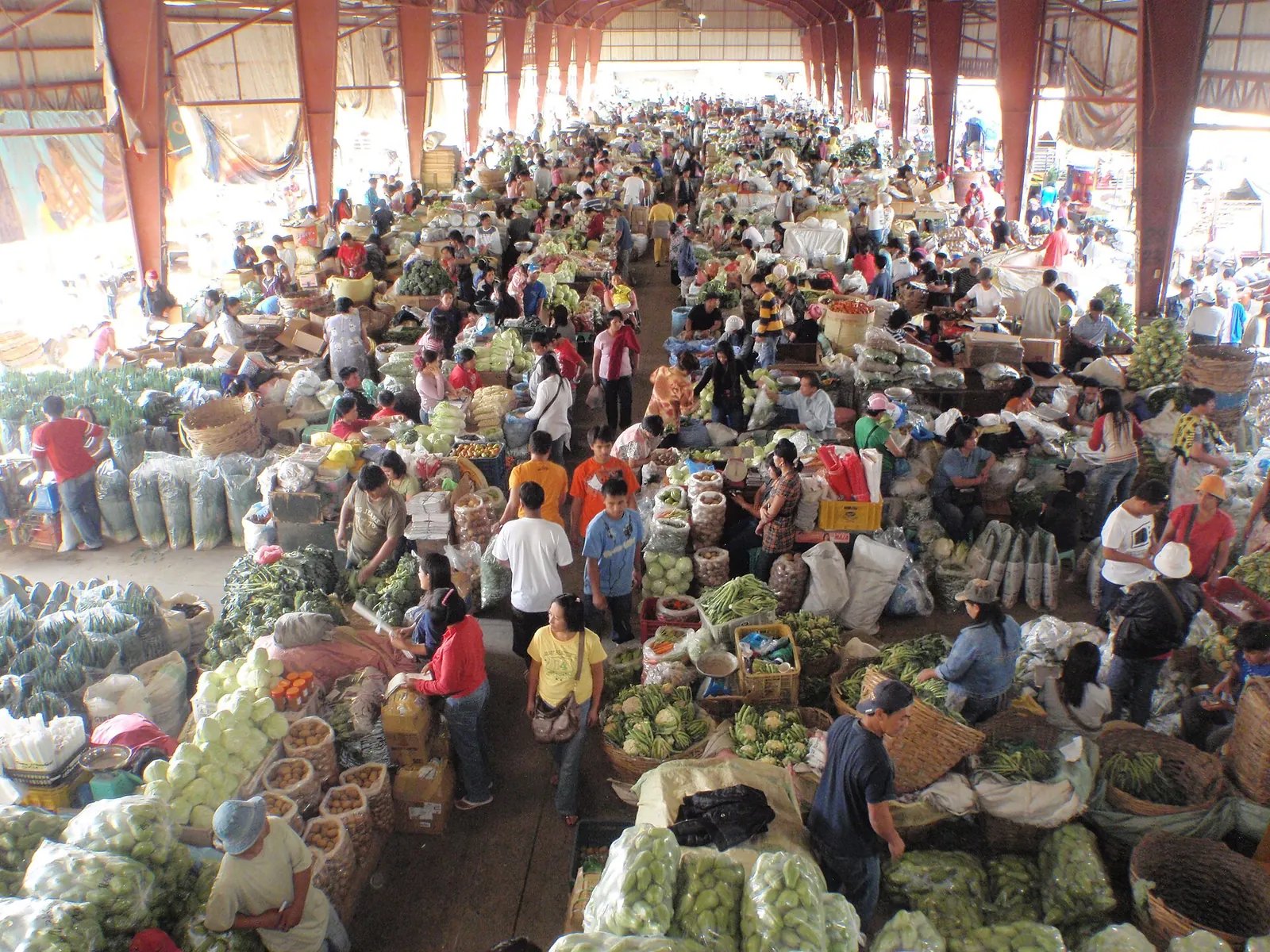 A busy market hall with baskets and stalls of vegetables in Baguio.