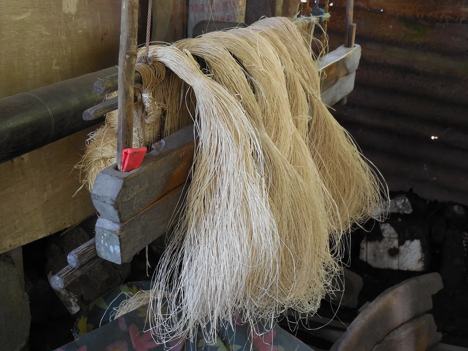 Pale abaca fibers draped across a wooden weaving loom in Banton, Romblon.